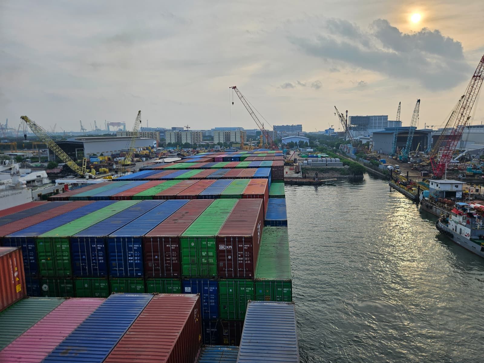 Loaded container vessel alongside a shipyard at sunset during the emergency anchor and chain replacement project