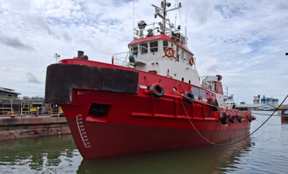 Red tugboat moored at a concrete dockside