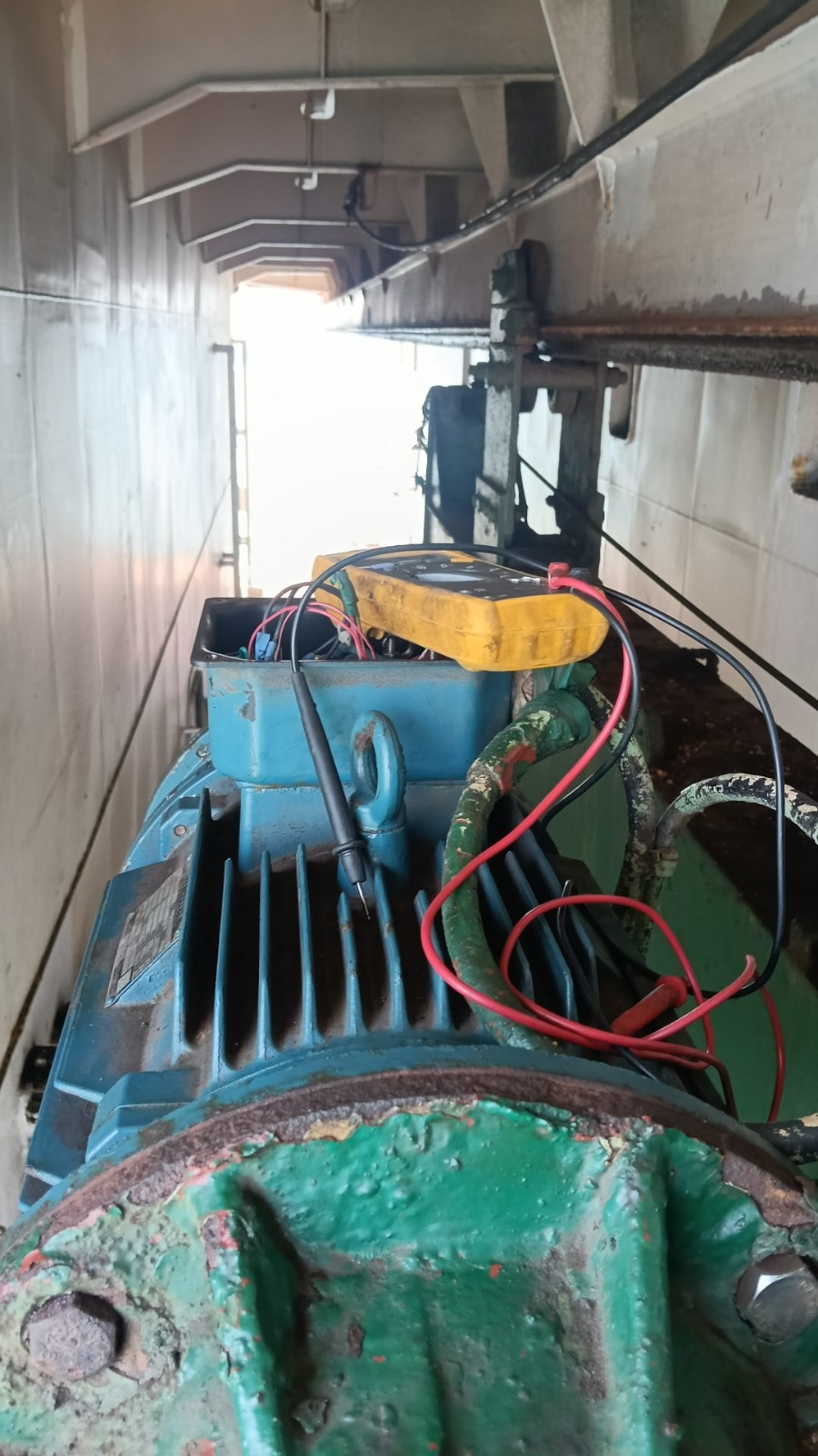 Industrial alternator motor with terminal box open during diagnostic testing with a digital multimeter