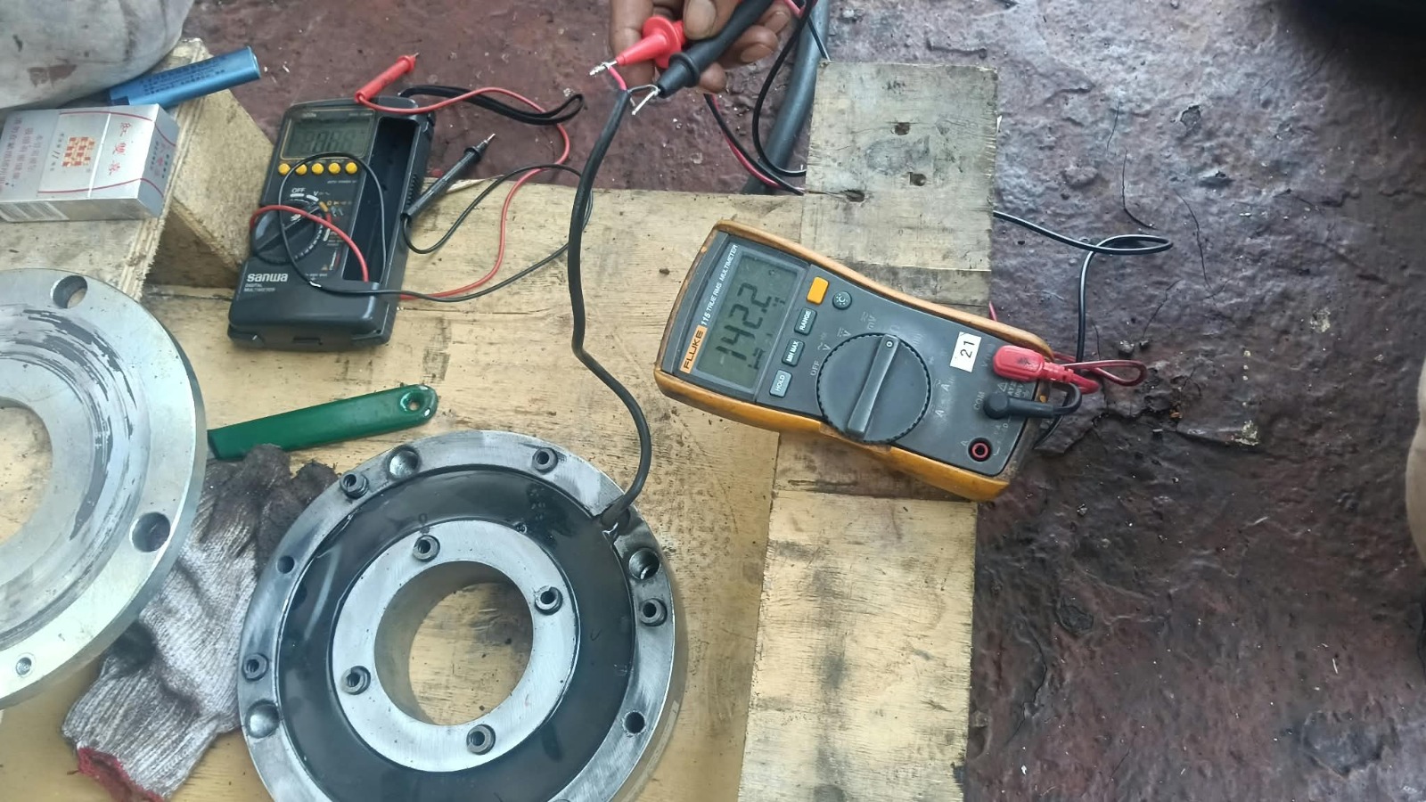 Coil resistance and insulation testing of alternator components using Fluke and Sanwa multimeters on a workbench