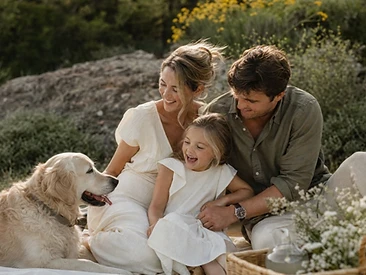 Famiglia seduta sull'erba con un Golden Retriever
