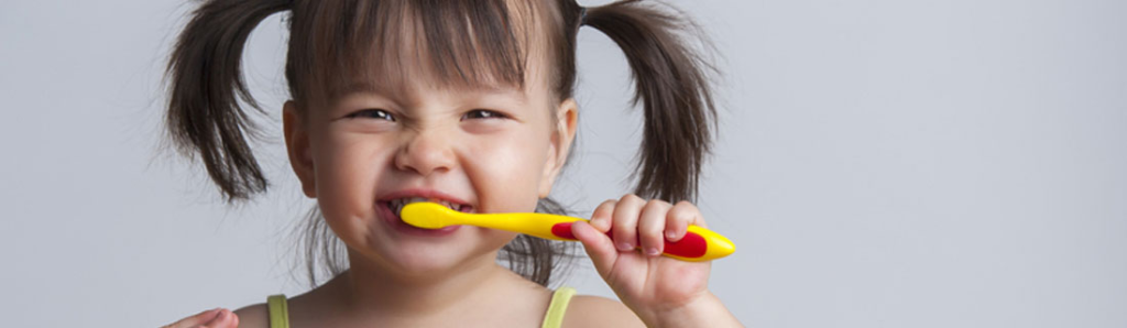 Child smiling while brushing their teeth — Mega Dental Richmond TX