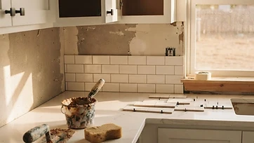 A nearly finished kitchen remodel with new shaker cabinets and subway tile backsplash in warm natural light