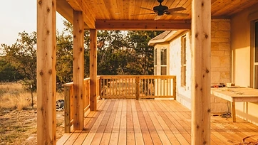 A freshly built covered wood back porch and deck with cedar posts in golden-hour light