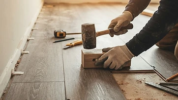 Luxury vinyl plank flooring being installed with a tapping block and mallet