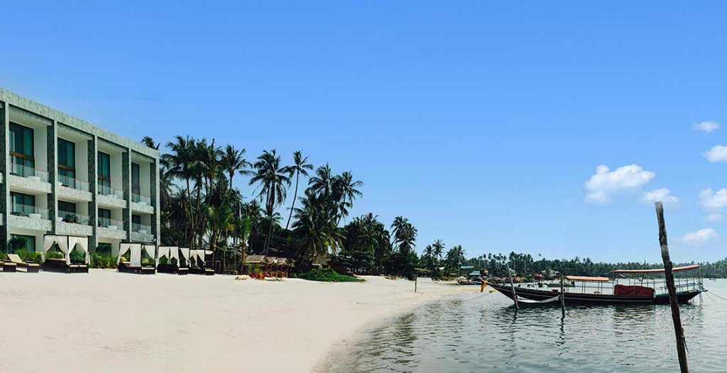 The Beach Samui resort beachfront with cabanas, palms and longtail boat