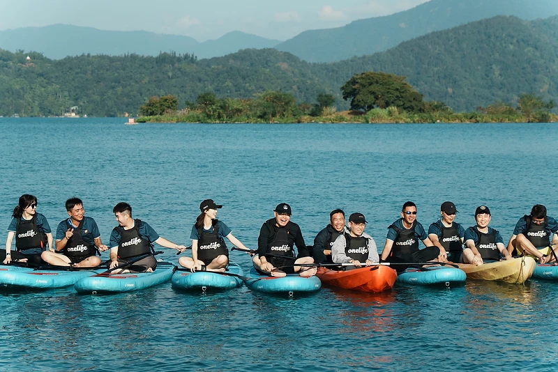團隊成員在湖上並排坐著 SUP 與獨木舟，分享旅行中的歡笑