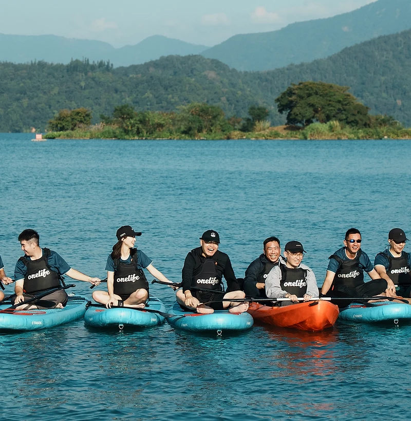 團隊成員在湖上並排坐著 SUP 與獨木舟,分享旅行中的歡笑