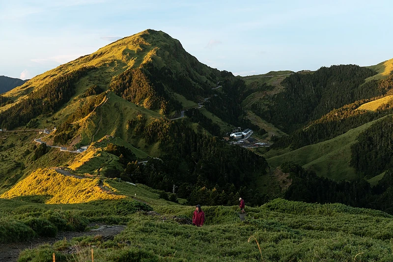 陽光照亮台灣山林與蜿蜒步道，旅人在山間探索