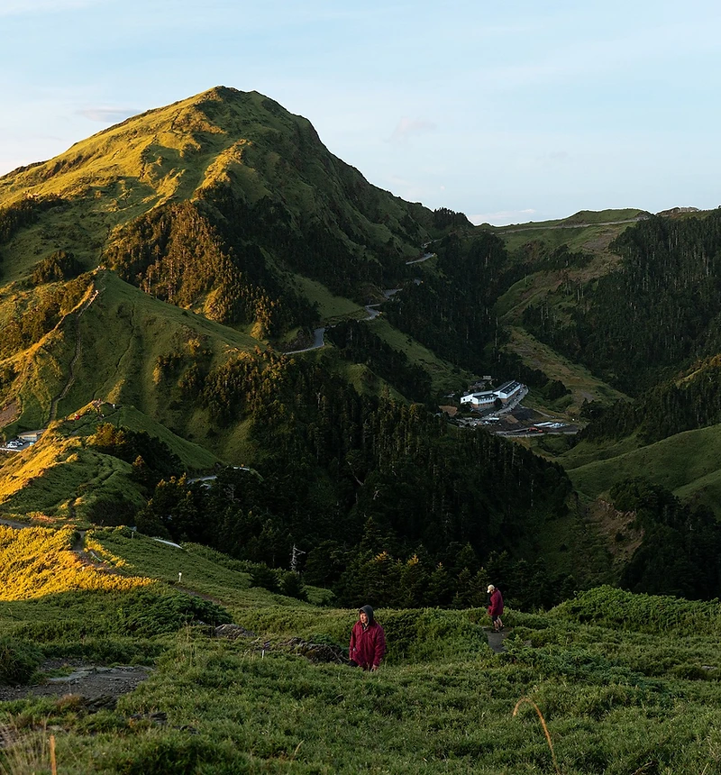 陽光照亮台灣山林與蜿蜒步道,旅人在山間探索