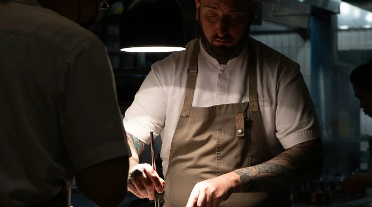 Chef plating a dish under a focused spotlight