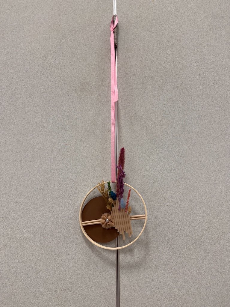 Suspension florale en cercle de bois avec fleurs séchées colorées, disque camel et ruban rose