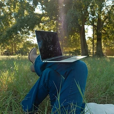 Emma working on her laptop in a golden field