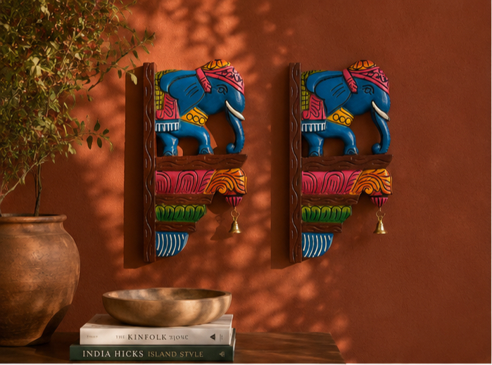 Hand-carved blue elephant brackets on a terracotta wall