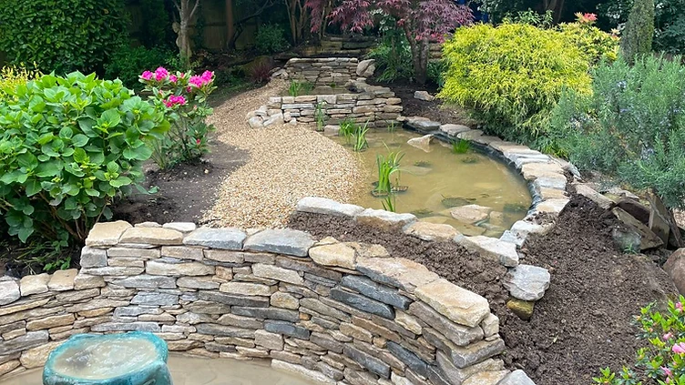 Garden with stone water feature and mature planting in Sunbury-on-Thames