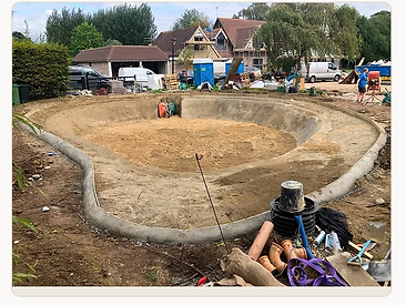 Kidney-shaped pool shell with concrete coping and drainage channel in Surrey