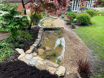 New pond with stone edging and aquatic planting established in Surrey