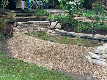 Garden pond with stone edging and marginal aquatic plants, Surrey