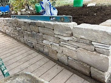 Dry-stone garden wall built with natural stone blocks and a spirit level in Surrey