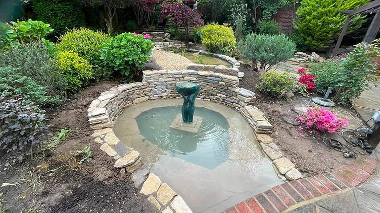 Completed circular pond with drystone walling and stone sculpture in Surrey