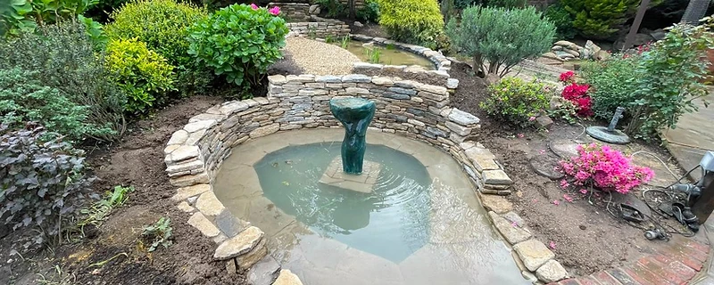 Completed ornamental pond with drystone walling in a Surrey garden