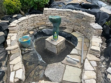 Circular stone pond being built with drystone coursing and a liner, Surrey