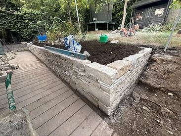 Natural stone retaining wall under construction with spirit level on the top course in Surrey
