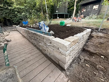 Natural stone retaining wall under construction with spirit level on the top course in Surrey