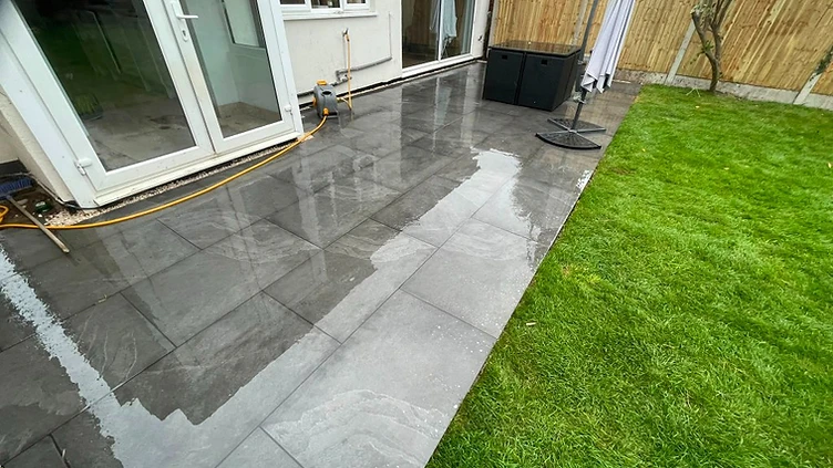 Grey porcelain slabs laid alongside freshly turfed lawn in Hersham