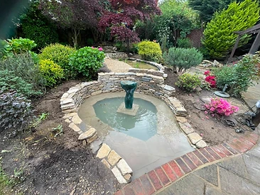 Garden with central stone water feature and paving in Surrey