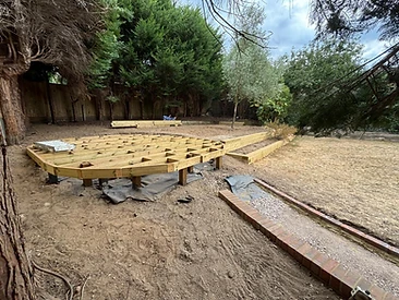 Circular decking frame under construction with timber sleeper retaining wall and brick path in Surrey