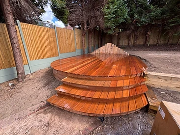 Completed circular hardwood deck with three curved steps and stained finish in Surrey