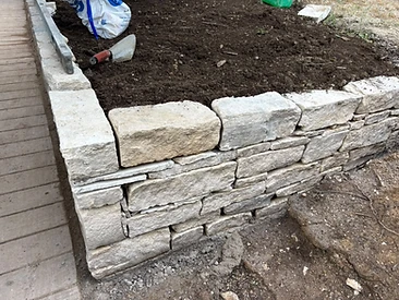 Natural stone wall corner under construction in a garden with spirit level in Surrey