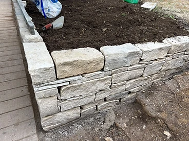 Natural stone wall corner under construction in a garden with spirit level in Surrey