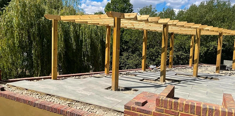 Completed timber pergola over porcelain paving with brick planters in Surrey