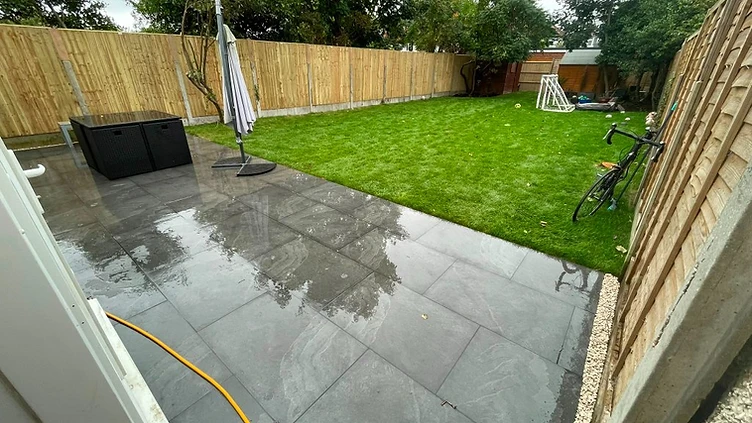 Grey porcelain patio with new turf and close-board fence in Walton-on-Thames