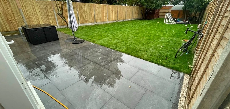 Fresh turf laid alongside grey porcelain patio and close-board fence in Surrey
