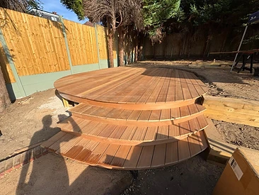 Finished circular landscape deck with curved steps and stained timber planks in Surrey