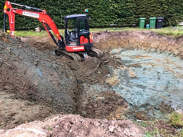 Compact excavator digging a pond excavation in clay soil in Surrey