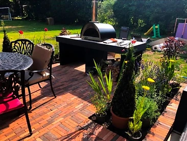 Outdoor kitchen with pizza oven on a herringbone brick patio in Surrey