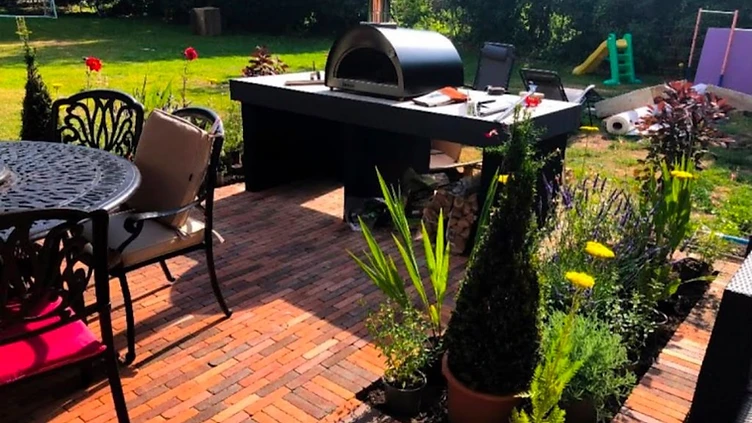 Outdoor kitchen with pizza oven on a herringbone brick patio in Surrey