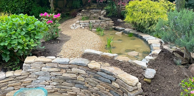 Garden with tiered stone water feature and naturalistic pond in Surrey