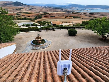 UniFi U7 Outdoor access point mounted on the rooftop overlooking the estate