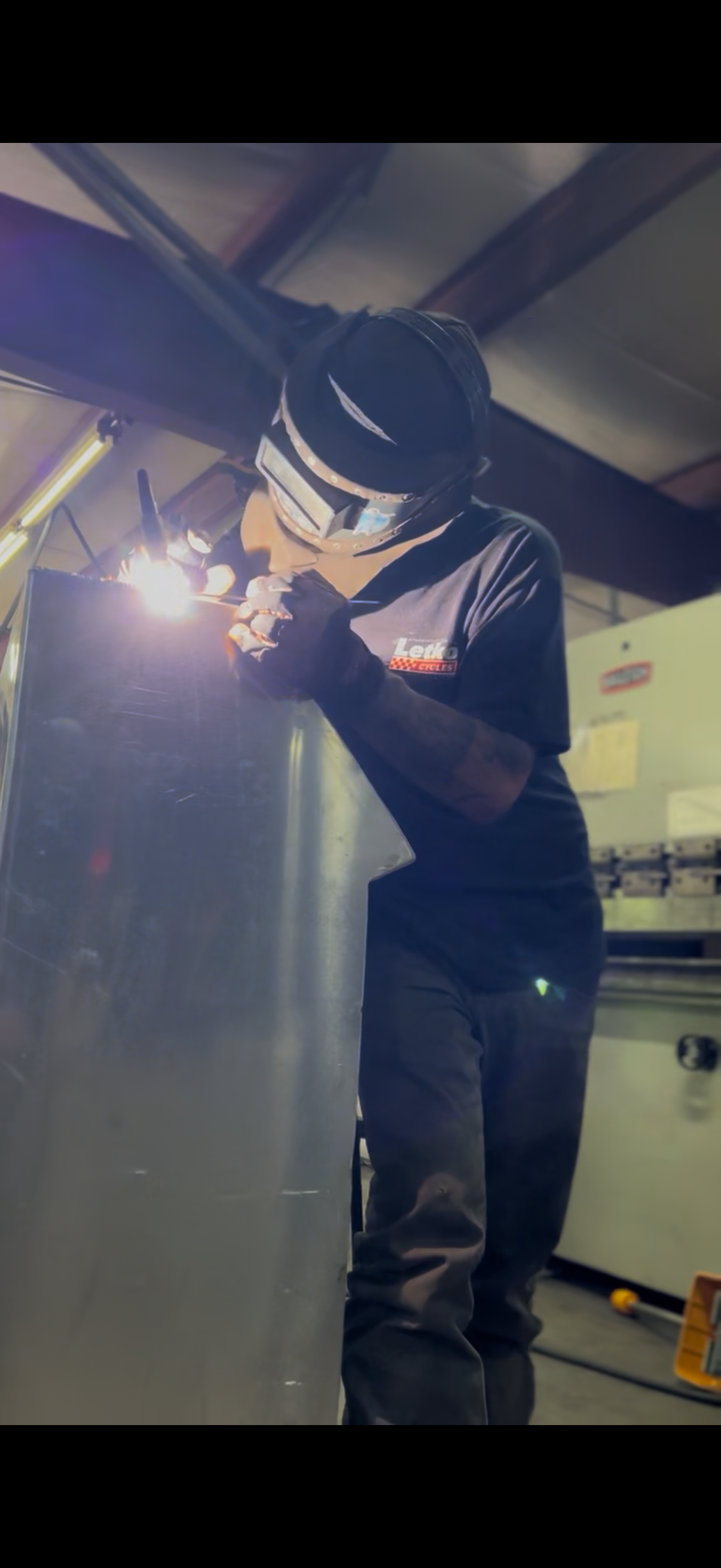 Rabideau Fabrication welder TIG welding a polished metal panel in the shop