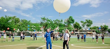 Weather balloon launch on a sports field with an astronaut