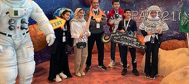 Students posing with an astronaut suit statue at a Space 2101 exhibit