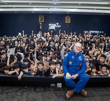 NASA astronaut in blue flight suit with a crowd of students