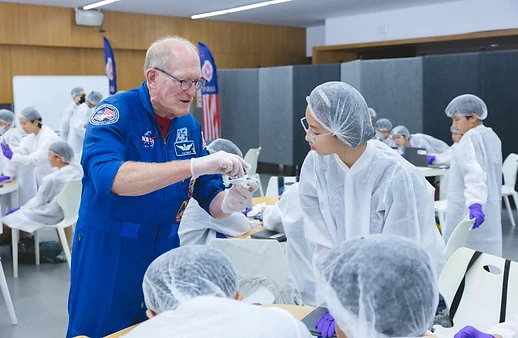 Astronaut demonstrating a model to a student in a lab coat