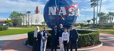 Students and mentors in front of the NASA logo sign