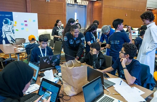 Students working on laptops with a NASA mentor